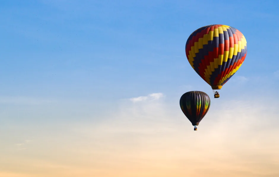 Two hot air balloons in flight at sunset.