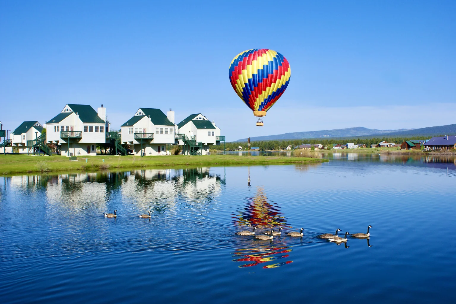 Pagosa-Springs-Hot-Air-Ballooning A hot air balloon taking off nearby a small lake and a few white houses in Pagosa Springs, Colorado.